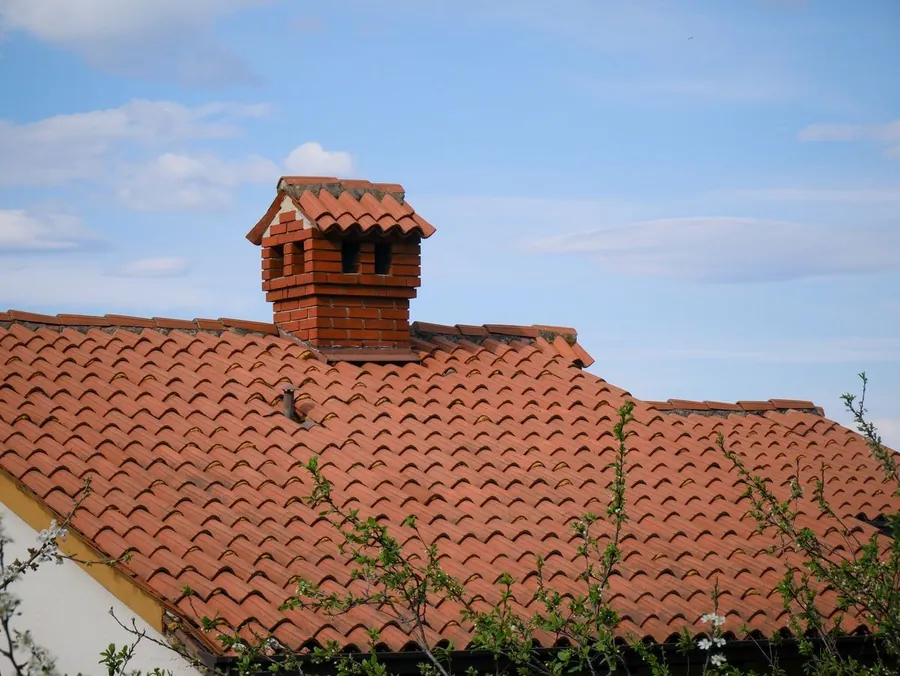 Brick chimney stack rising through a clay plain tile roof on an older Croydon house