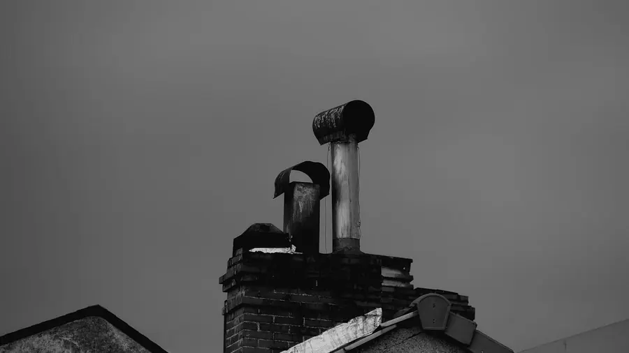 Brick chimney stack fitted with metal flue terminals and hooded cowls that keep rain out while letting air through