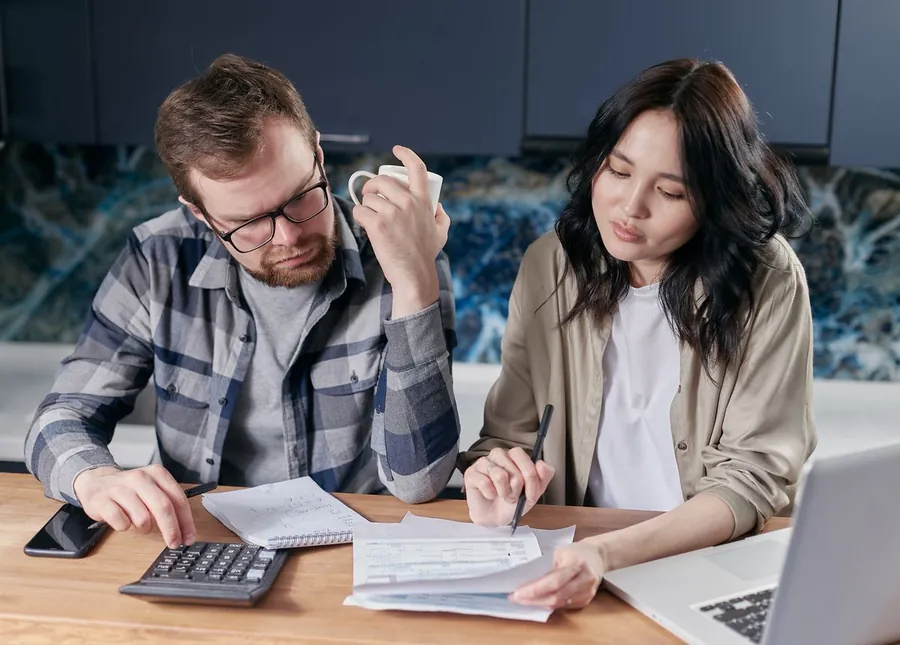 A couple at a kitchen table weighing up repair costs before selling their house