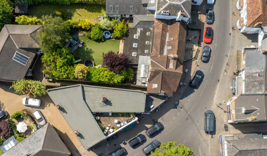 Looking straight down on a large flat roof tucked in behind pitched tiled roofs and back gardens, where nobody at street level ever sees it