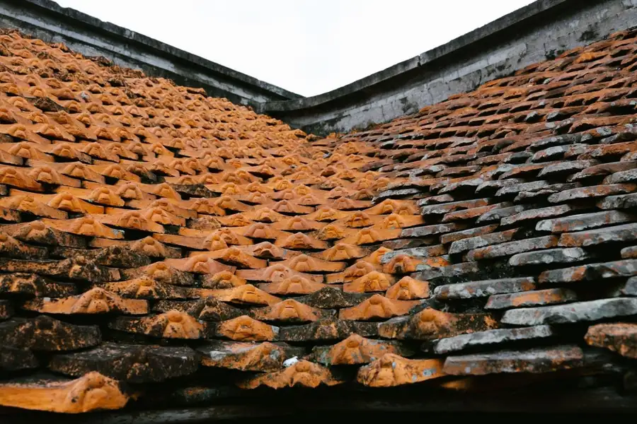 Weathered old clay roof tiles with worn and flaking surfaces