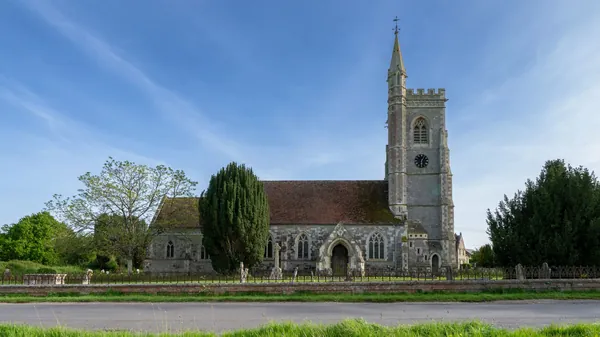 English stone parish church with a tall tower and churchyard trees