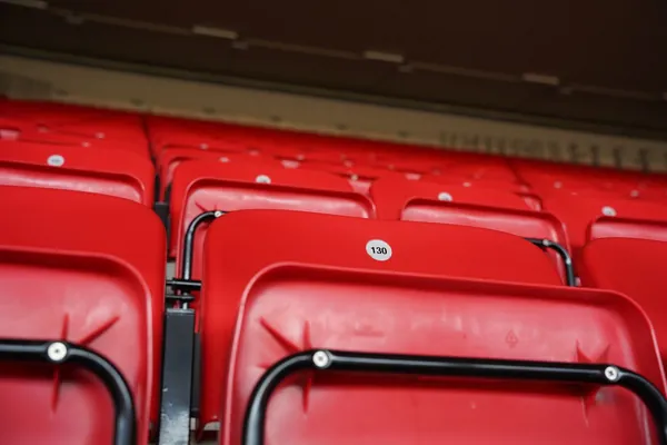 Rows of red seats in the stand of a football stadium