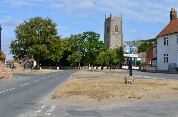 Village road leading to an old church with a square tower