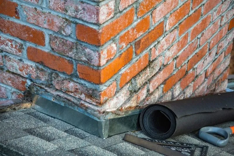Flat roof detail where the covering meets a brick upstand, a common leak point in Croydon