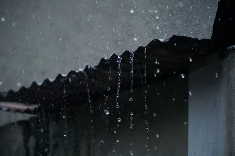 Heavy rain running off the edge of a roof at night in Croydon